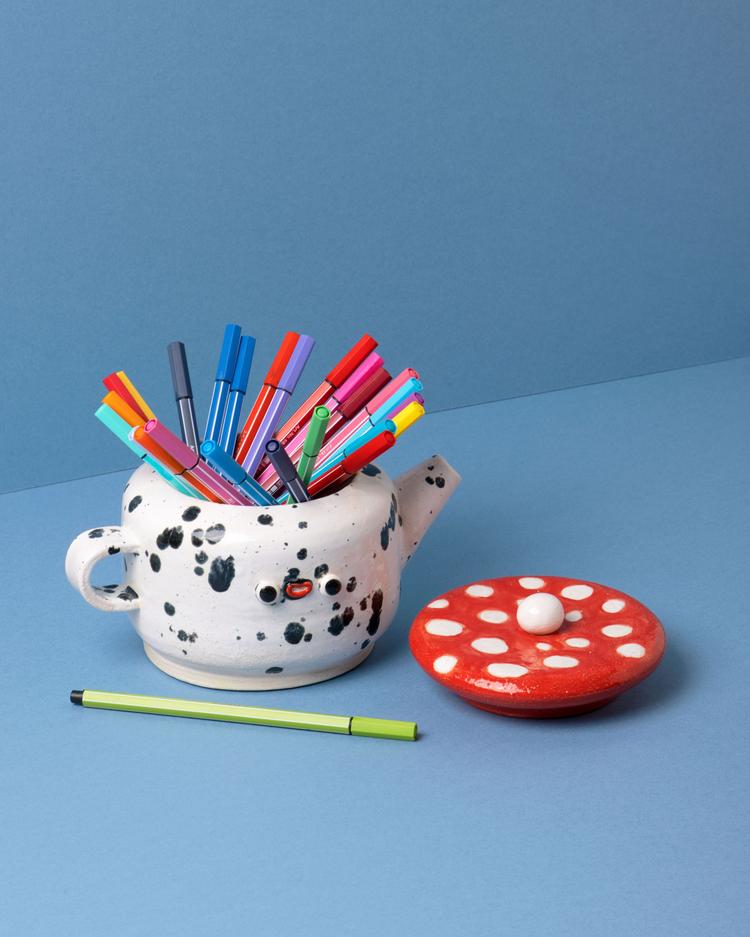 White teapot with black speckles and a red mushroom lid