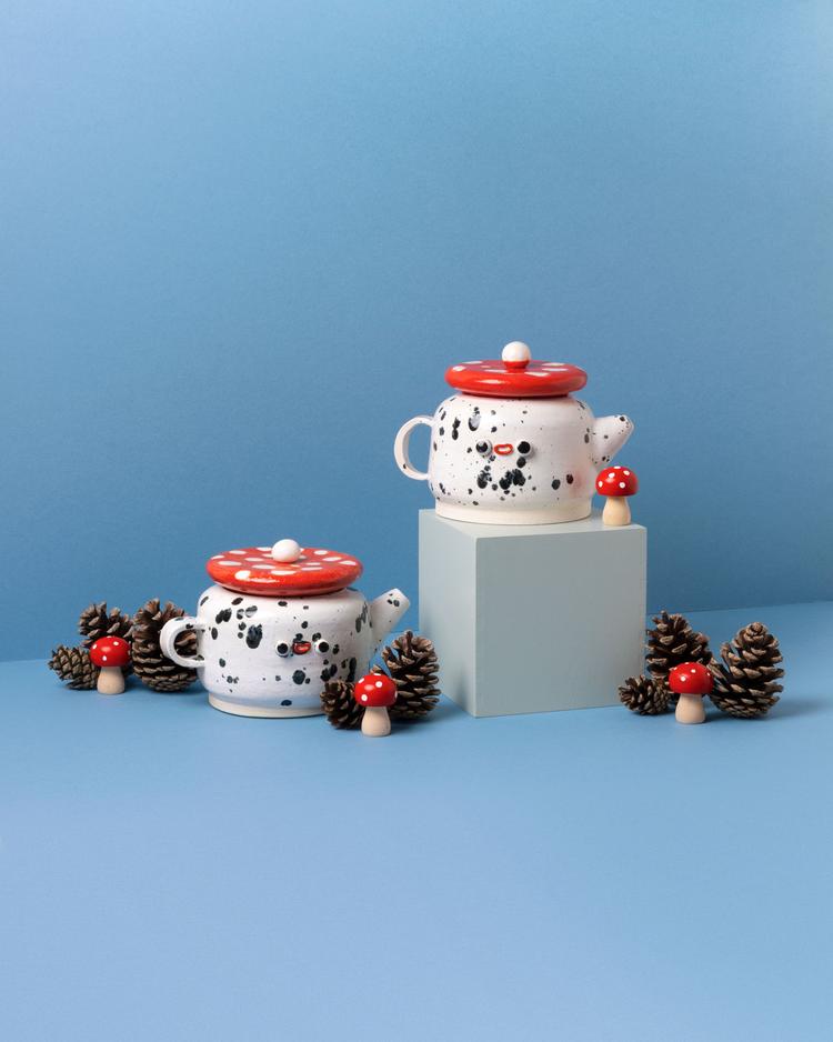 White teapots with black speckles and a red mushroom lid